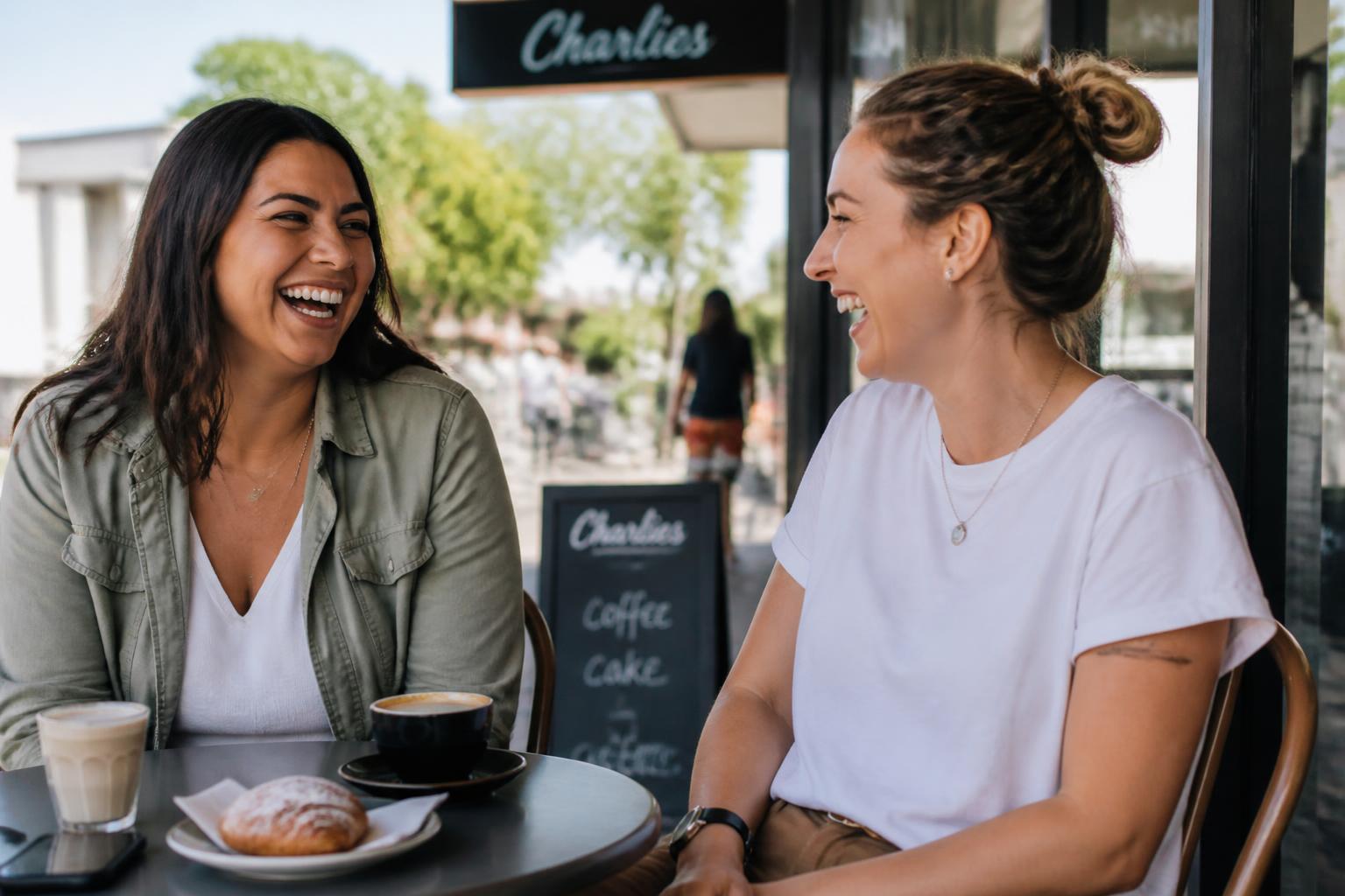 Two Australian adults meeting for coffee for the first time at a local café, chatting and smiling